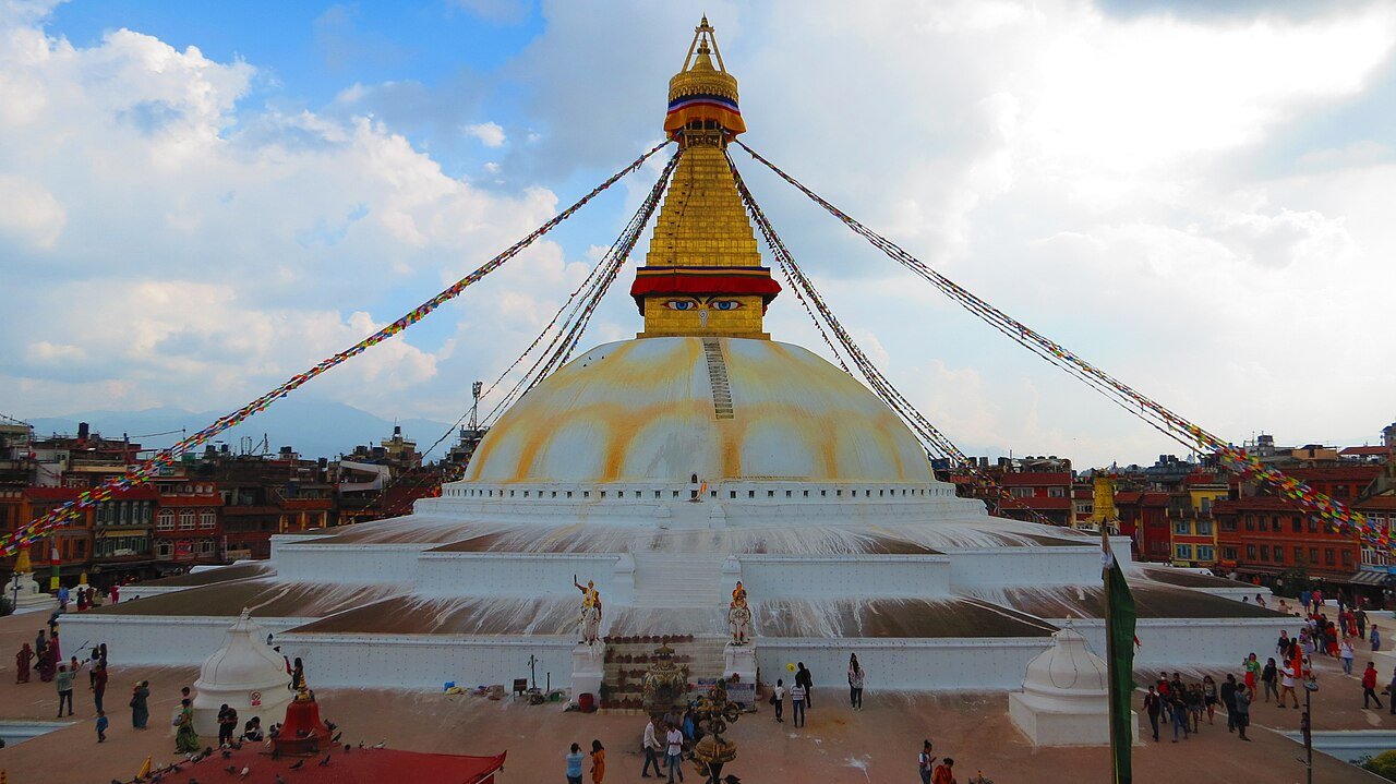 Boudhanath Stupa with prayer flags and people in the surrounding square