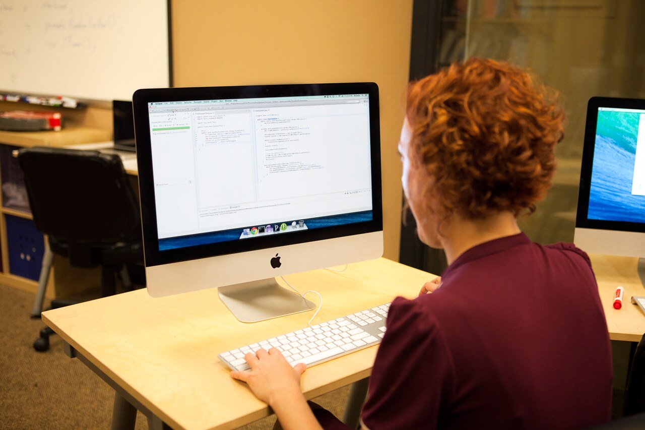A programmer working at a desktop computer with code on screen